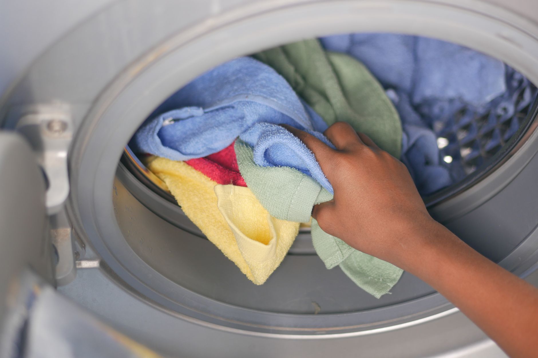 Main chargeant des serviettes dans un lave-linge à chargement frontal