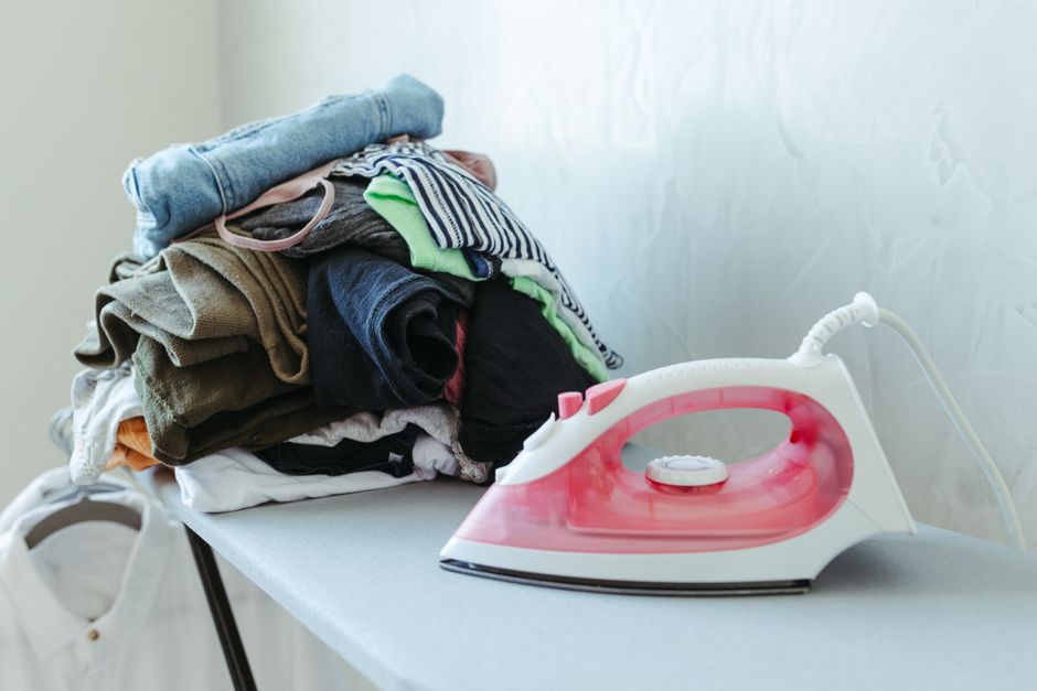 Pile de vêtements et fer posé sur une planche à repasser