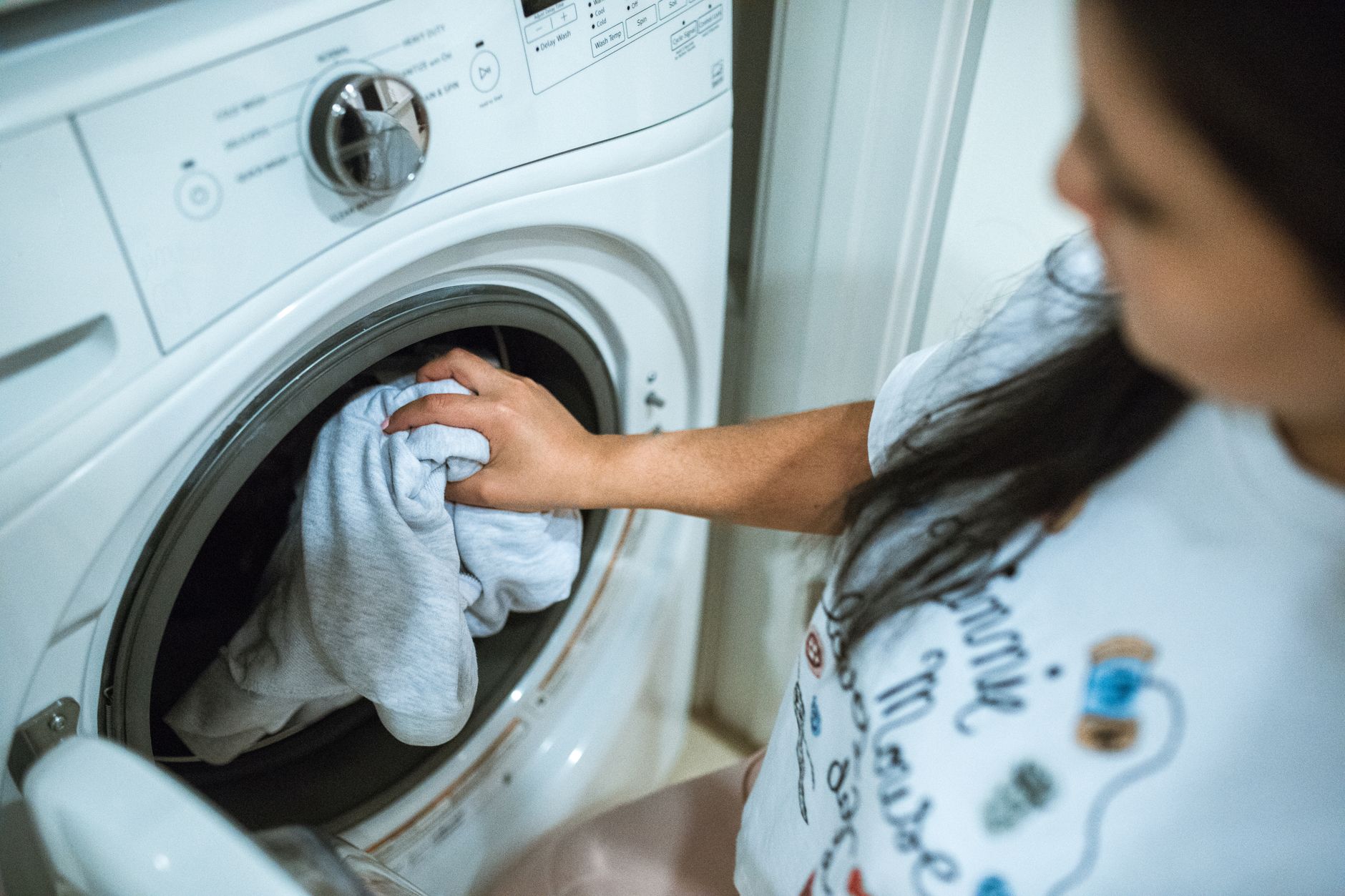 Femme chargeant du linge dans une machine à laver à la maison