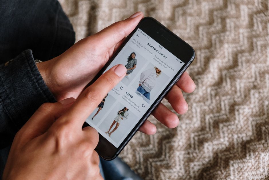 Personne faisant défiler des vêtements sur un téléphone