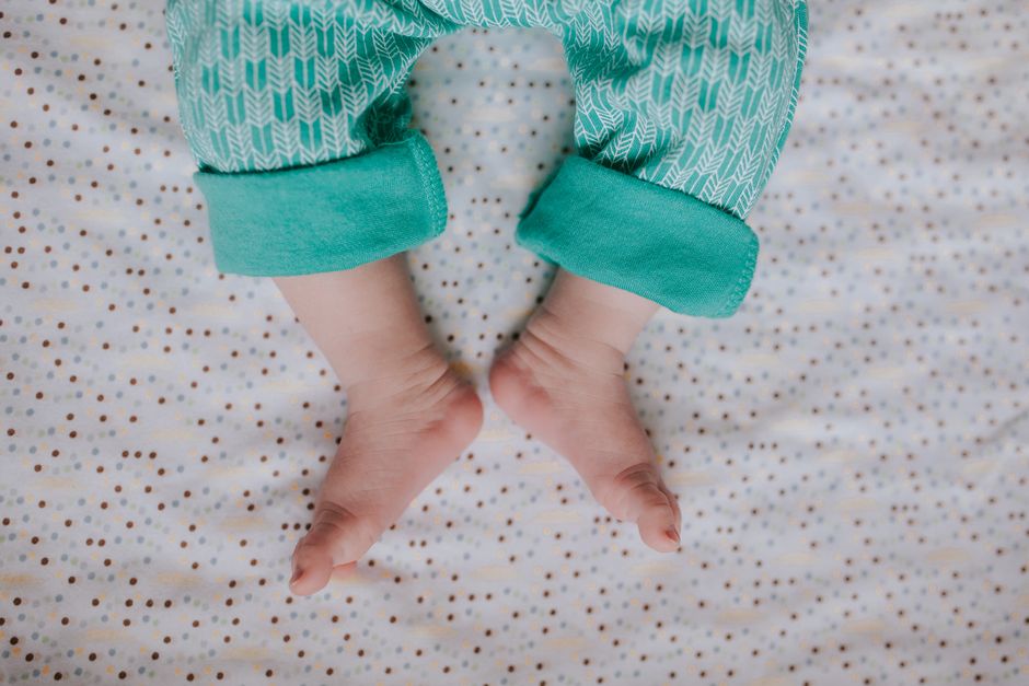 Pieds de bébé en pyjama posés sur une couverture