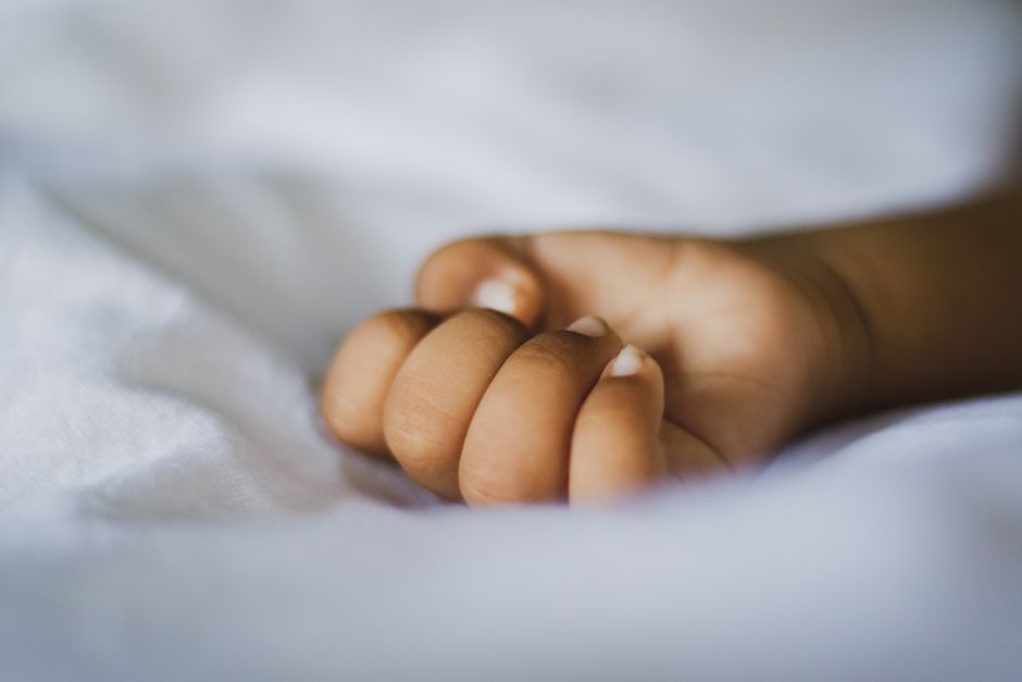 Main d'enfant posée sur un tissu blanc