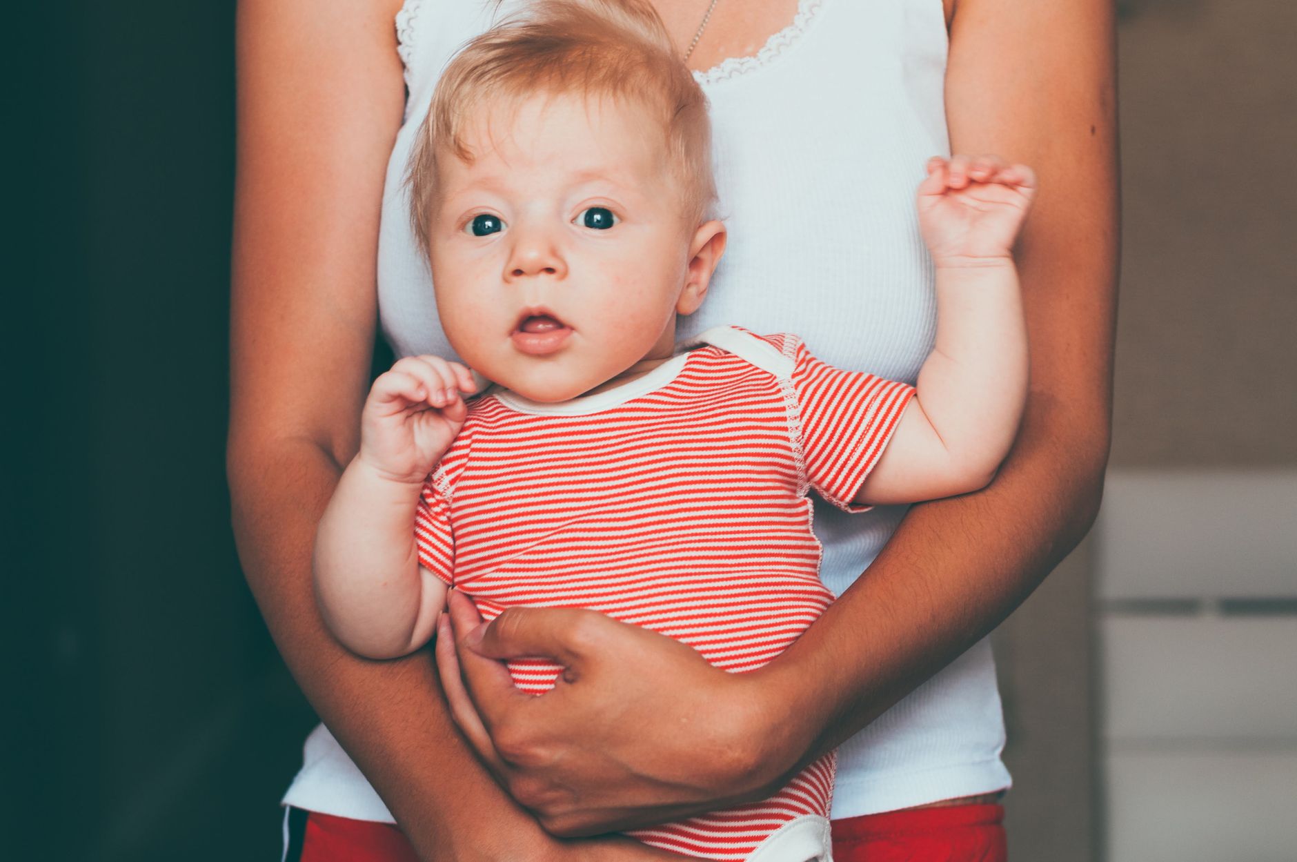 Bébé porté dans les bras, vêtu d’un body à rayures