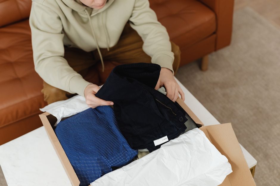 Personne sortant des vêtements d'un carton sur une table